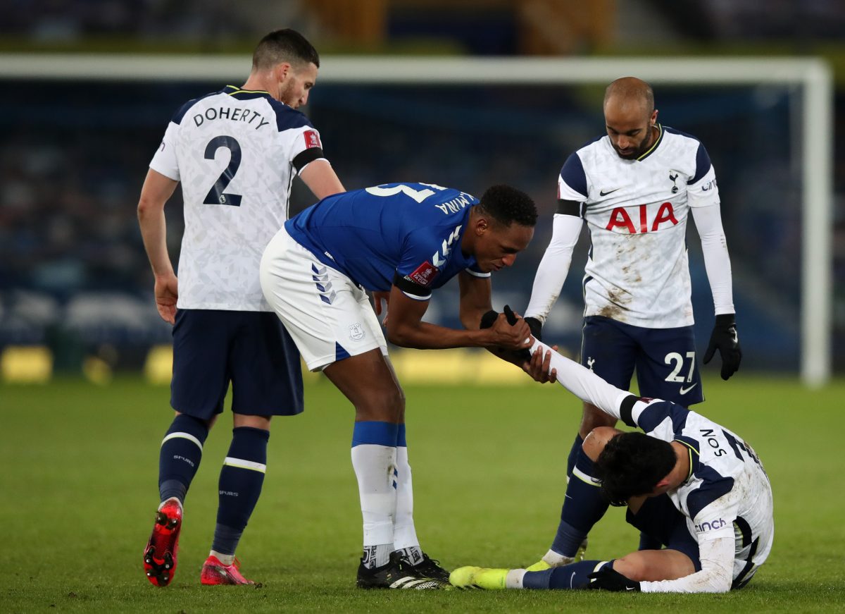 Son Heung-min of Tottenham Hotspur is helped up by Yerry Mina of Everton as Lucas Moura and Matt Doherty watch on during an FA Cup game.