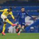 Yves Bissouma of Brighton and Hove Albion takes a shot under pressure from Hakim Ziyech of Chelsea.