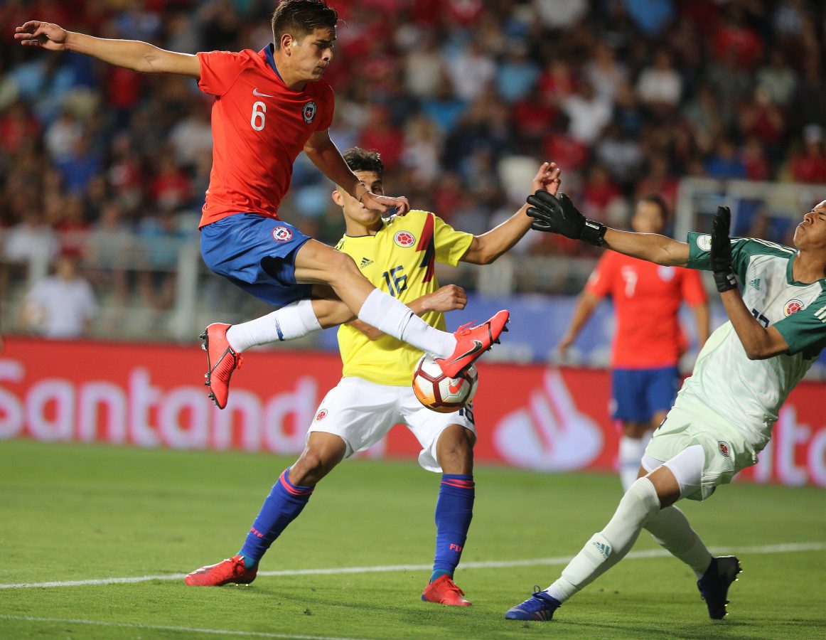 Chile's Axel Rios vies for the ball with Colombia's goalkeeper Kevin Mier during their South American U-20 football match. 