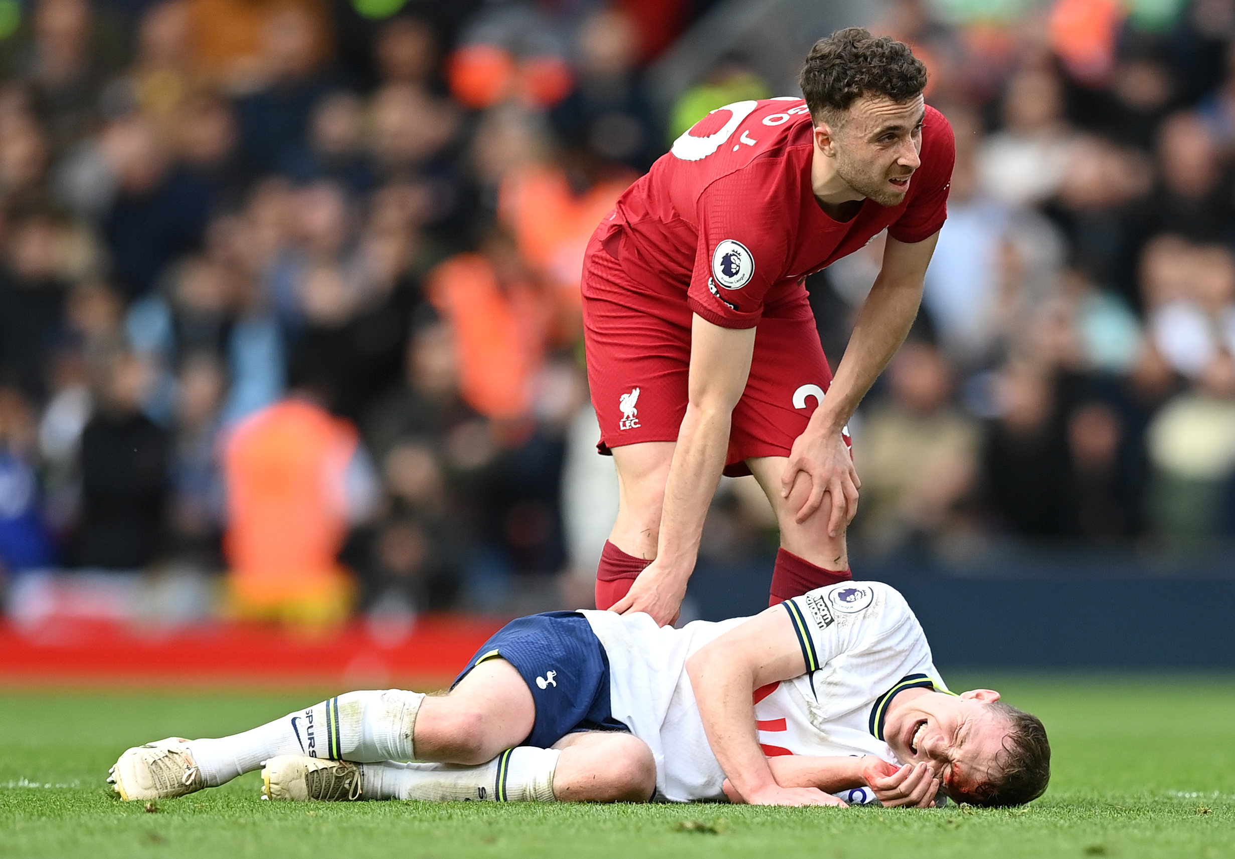 Diogo Jota of Liverpool with Oliver Skipp of Tottenham Hotspur after he goes down with an injury.