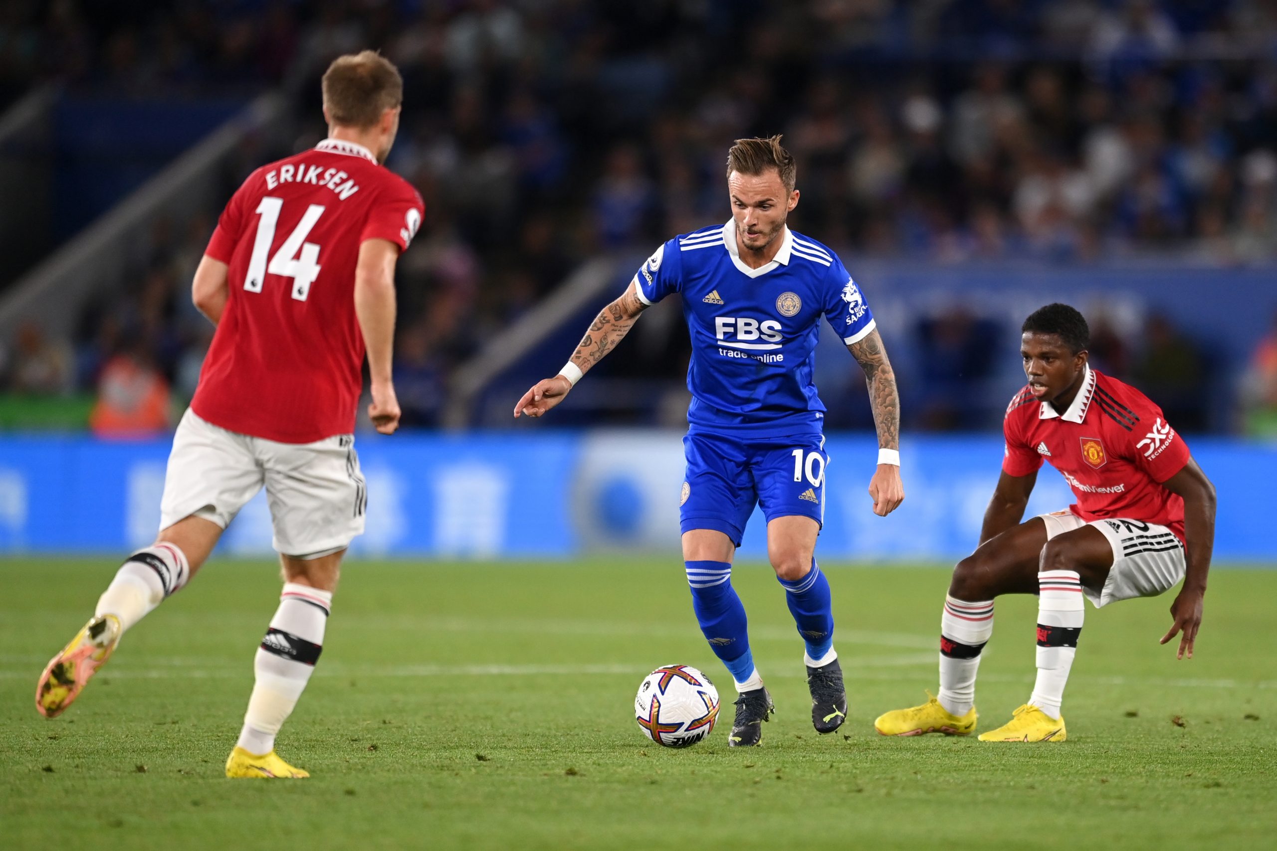 James Maddison of Leicester City is challenged by Christian Eriksen and Tyrell Malacia of Manchester United.
