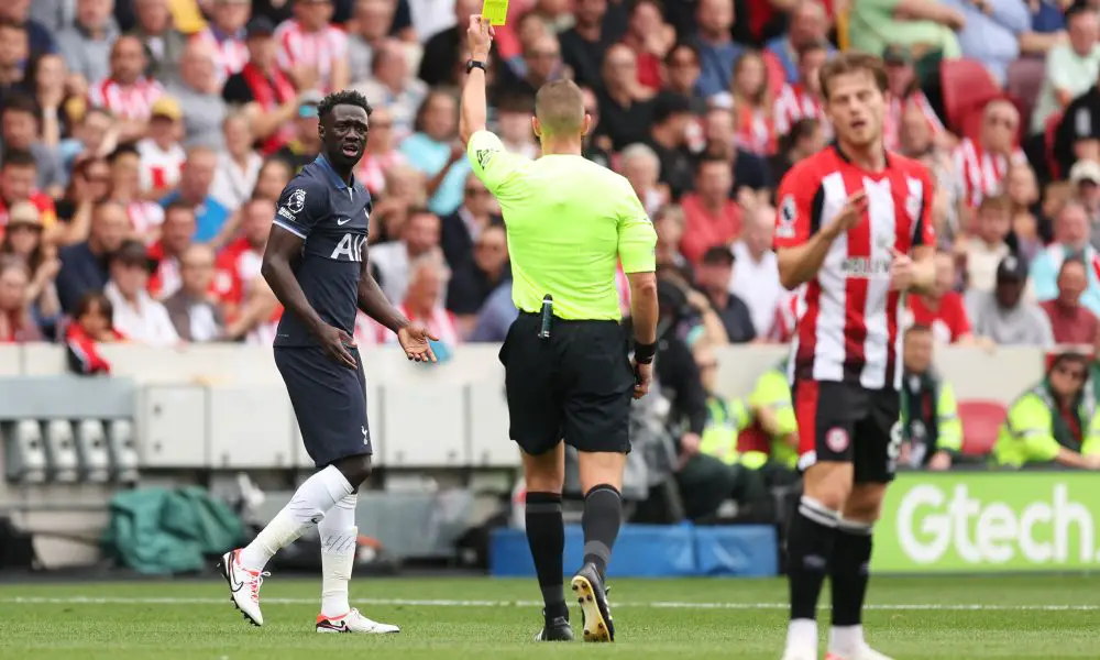Referee Robert Jones shows a yellow card to Davinson Sanchez of Tottenham Hotspur.