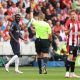 Referee Robert Jones shows a yellow card to Davinson Sanchez of Tottenham Hotspur.