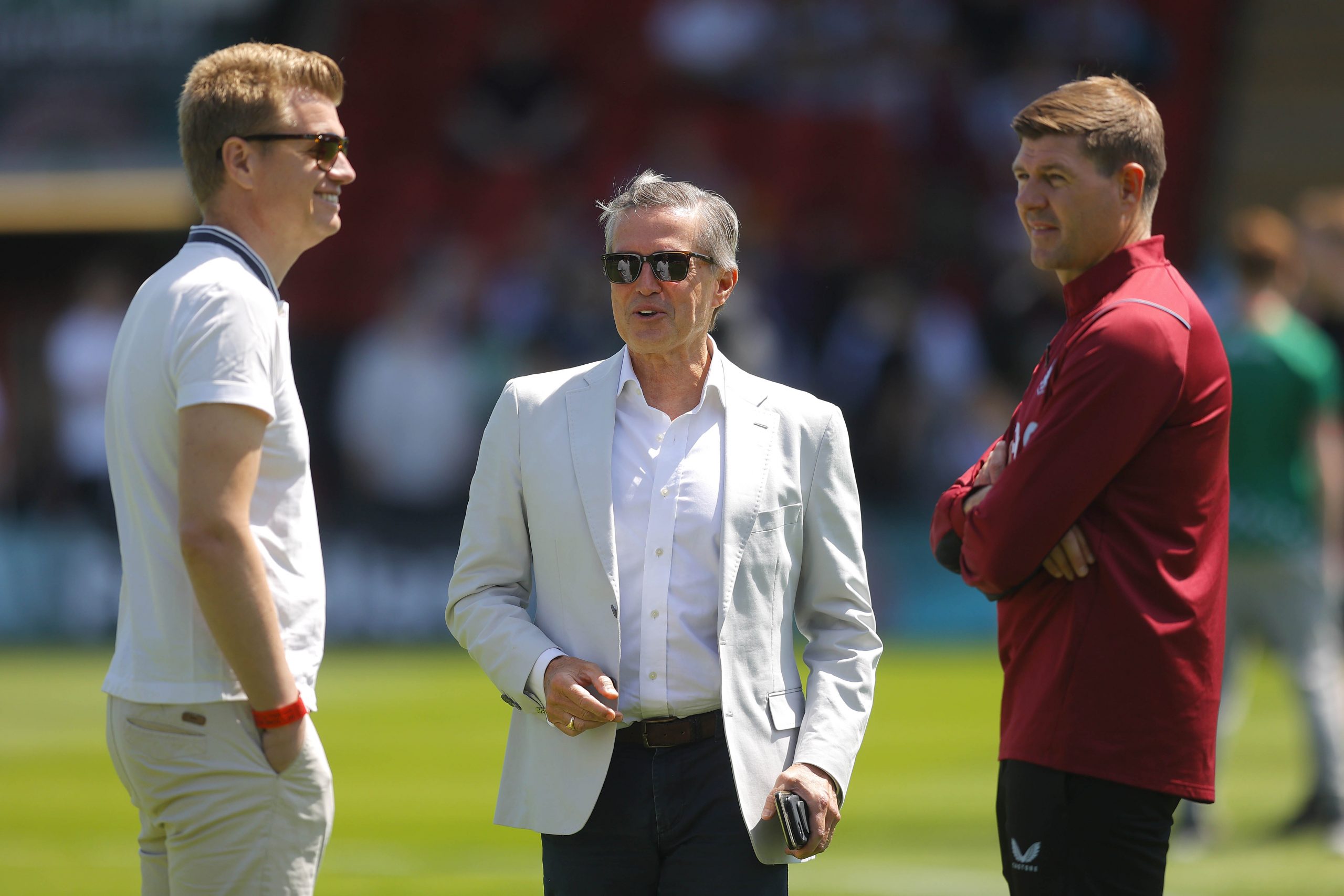Aston Villa Chief Executive Christian Purslow (C) chats to Sporting Director Johan Lange (L) and manager Steven Gerrard (R).